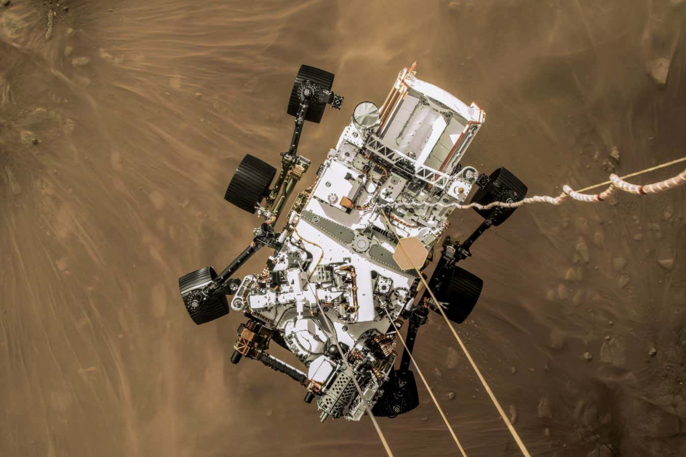 NASA?s Mars 2020 Perseverance rover, moments before landing in Jezero Crater, February 18, 2021. The photo was taken from the rocket-powered descent stage, which is lowering the rover to the ground on cables while hovering. At the moment of touchdown, the rover cut its cables, and the descent stage flew away to crash at a safe distance. ? NASA/JPL-Caltech PAGE 214