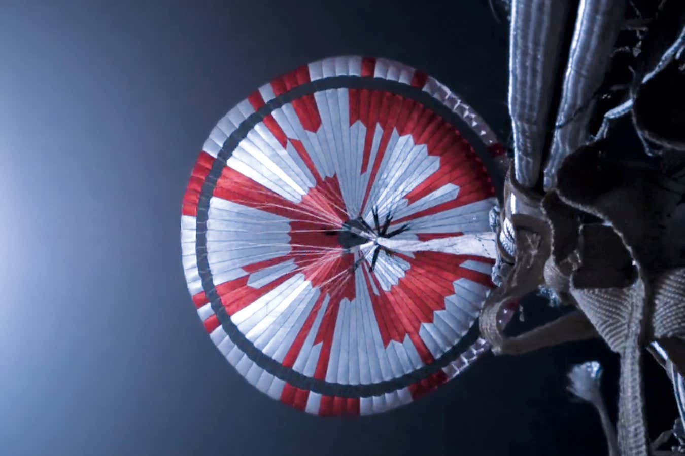 A camera mounted to the top deck of the Perseverance rover captured the deployment and inflation of its supersonic parachute during its descent to Mars in 2021. The red-and-white stripes both help engineers map the motions of the parachute and encode two secret messages: the geographic coordinates of the Jet Propulsion Laboratory and the lab motto ?dare mighty things.? PAGE 46 ? NASA/JPL-Caltech