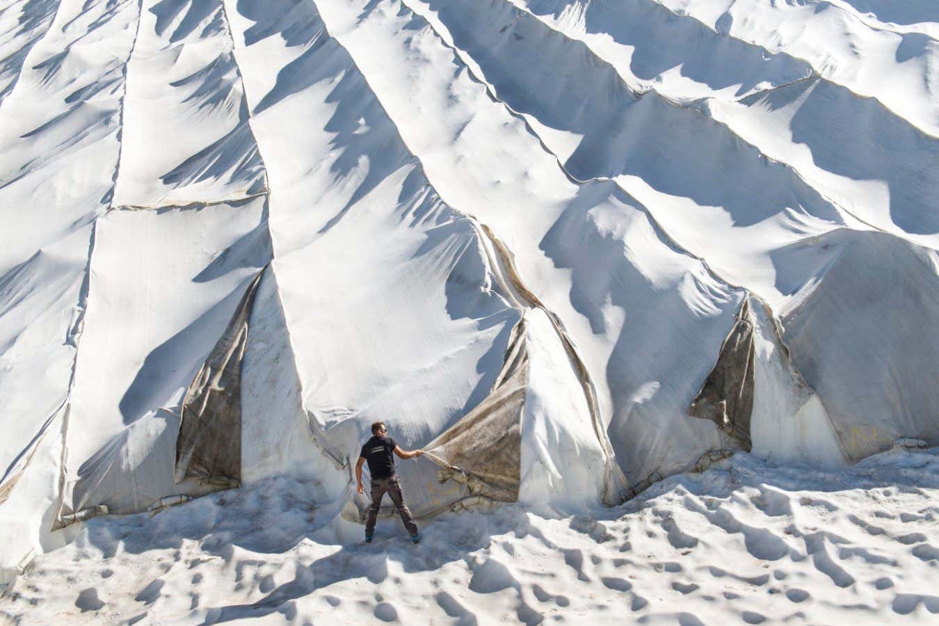 Removal: A worker unhooks the geotextile sheets during autumn. The sheets are removed in preparation for the first snowfall, which, along with artificial snow, help to stabilise the glacier. However, the on-going effects of climate change threaten the glacier?s survival.