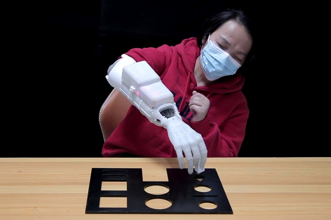 A woman with a hand amputation picking an object up while wearing the prosthetic